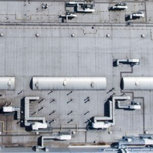 Aerial top view of a factory roof showcasing industrial pipes and structures.