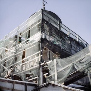 View of a historic church covered in scaffolding and mesh during renovation work.